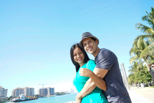 istock Beautiful couple standing next to the beach having fun facing camera smiling while hugging each other 1144399976