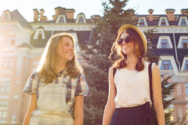 portrait de deux belles filles souriantes, adolescents 13, 14 ans, gros plan, filles parlant riant et marchant dans la ville d’été. - friendship early teens 13 14 years city street photos et images de collection