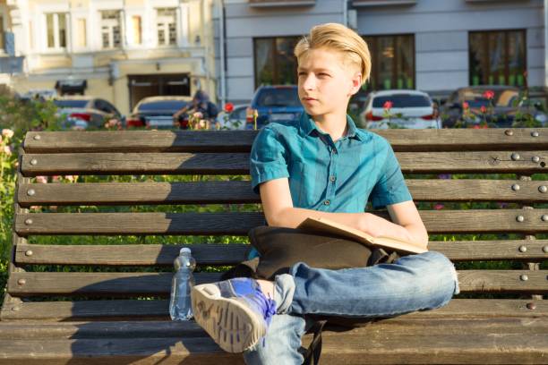 odkryty portret nastoletniego chłopca 13, 14 lat siedzącego na ławce w parku miejskim. - nature sitting 13 14 years cute zdjęcia i obrazy z banku zdjęć