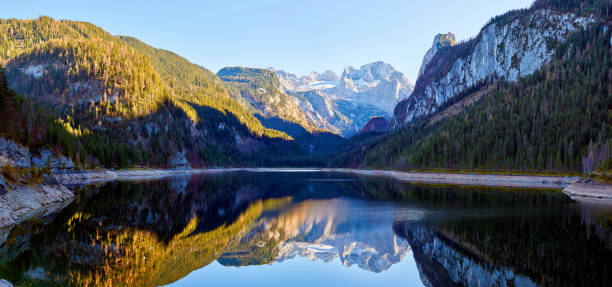 Beautiful Gosausee lake landscape with Dachstein mountains, forest, clouds and reflections in the water in Austrian Alps. Salzkammergut region.