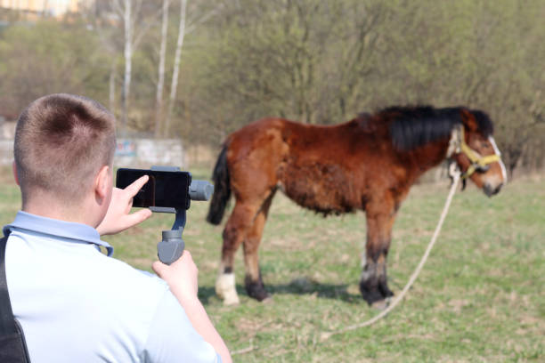 istock A young man videotaping on a smartphone. Uses gimbal to get smooth shots. Controls the recording by touching the screen. 1144405201