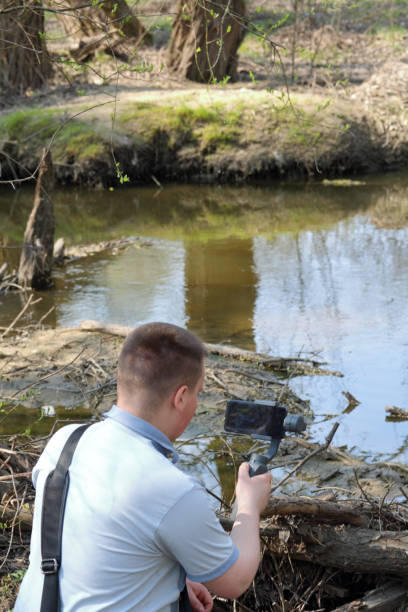 istock A young man videotaping on a smartphone. Uses gimbal to get smooth footage. Closely watching the movie shooting. 1144405218