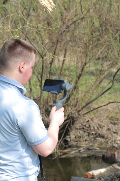 istock A young man videotaping on a smartphone. Uses gimbal to get smooth footage. Closely watching the movie shooting. 1144405245