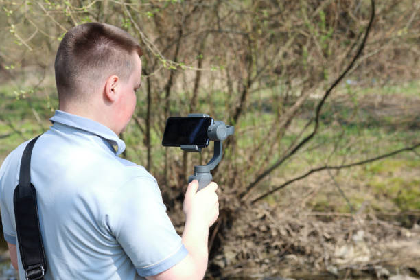 istock A young man videotaping on a smartphone. Uses gimbal to get smooth footage. Closely watching the movie shooting. 1144405250
