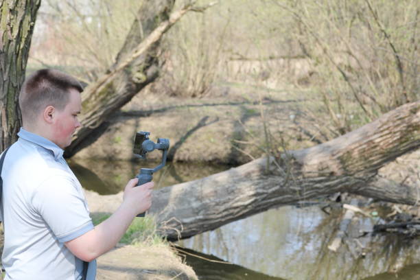 istock A young man videotaping on a smartphone. Uses gimbal to get smooth footage. Closely watching the movie shooting. 1144405251