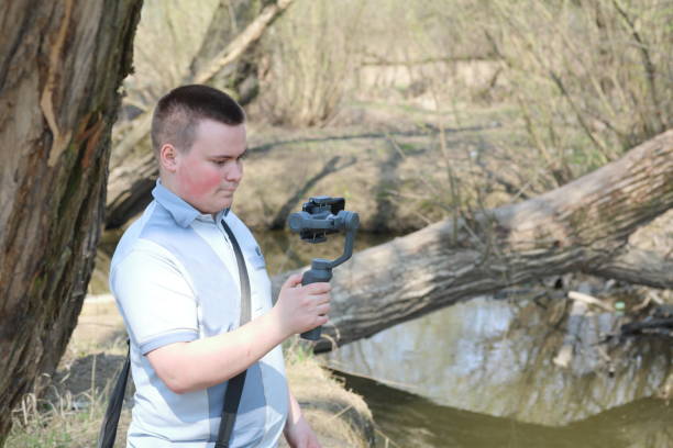 istock A young man videotaping on a smartphone. Uses gimbal to get smooth footage. Closely watching the movie shooting. 1144405255