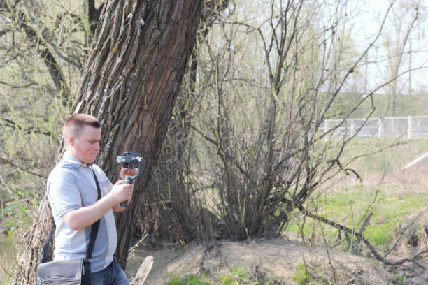 istock A young man videotaping on a smartphone. Uses gimbal to get smooth footage. Closely watching the movie shooting. 1144405263