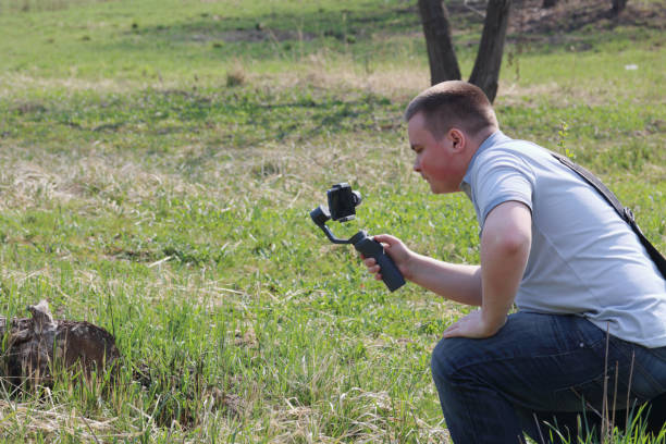 istock A young man videotaping on a smartphone. Uses gimbal to get smooth footage. Closely watching the movie shooting. 1144405269