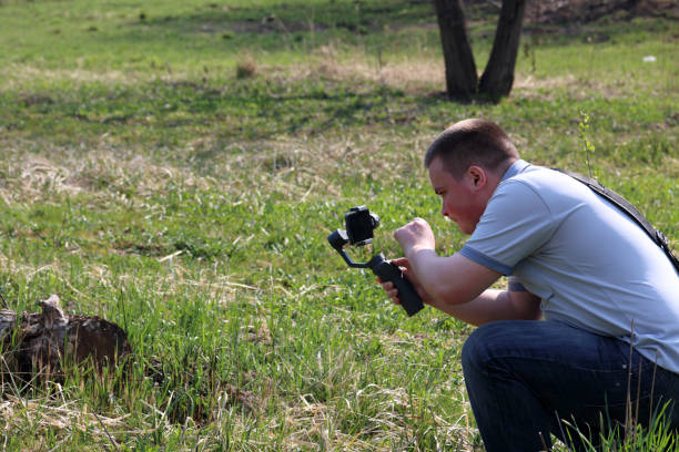 istock A young man videotaping on a smartphone. Uses gimbal to get smooth shots. Controls the recording by touching the screen. 1144405271