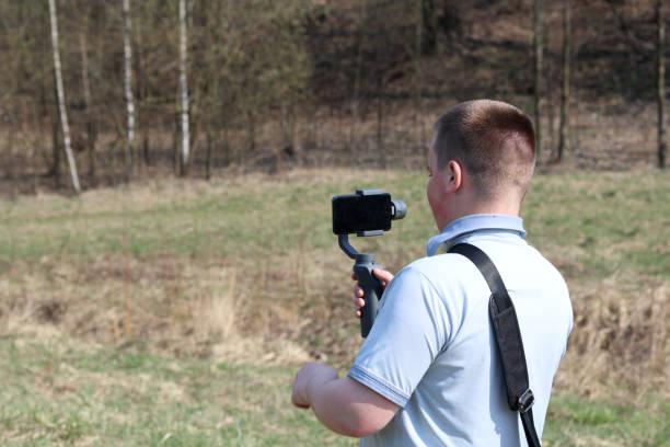 istock A young man videotaping on a smartphone. Uses gimbal to get smooth footage. Closely watching the movie shooting. 1144405277