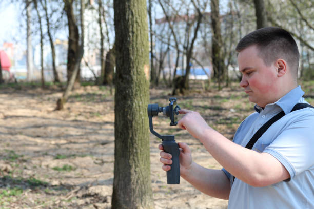istock A young man videotaping on a smartphone. Uses gimbal to get smooth shots. Controls the recording by touching the screen. 1144405331