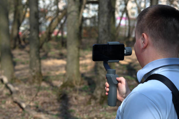istock A young man videotaping on a smartphone. Uses gimbal to get smooth footage. Closely watching the movie shooting. 1144405341