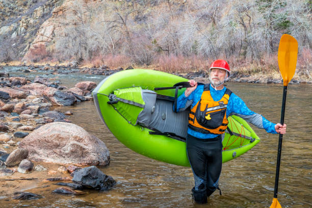 senior paddler carrying  inflatable whitewater kayak
