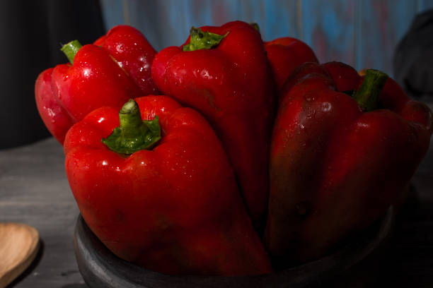 istock FRESH RED PEPPERS IN THE FOREGROUND IN BLACK CLAY BOWL 1144410909