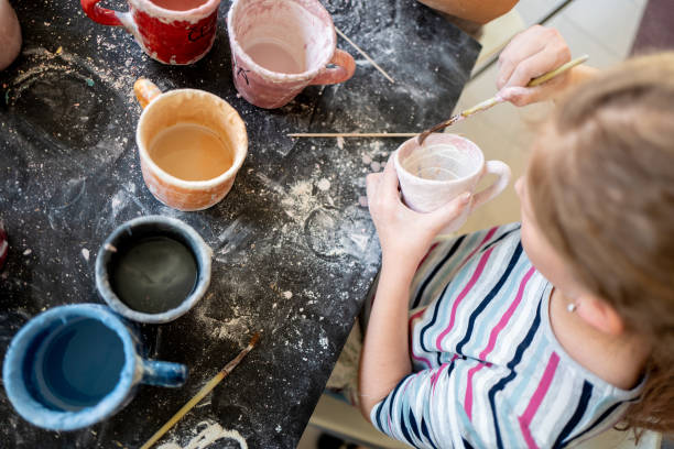 istock Girl concentration on painting pottery cups 1144416737
