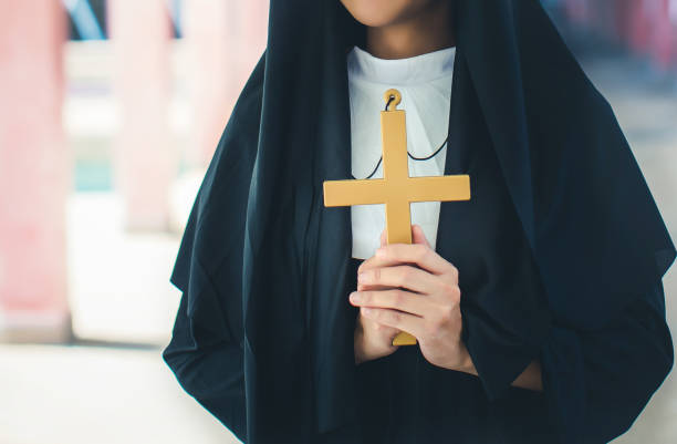 Religious nun in religion concept. Hands praying to the GOD while holding a crucifix symbol. Religious nun in religion concept. Hands praying to the GOD while holding a crucifix symbol. Nun holding a cross in his hands. Human hands holding a cross holy and prayed for blessings from God. nun praying cross human hand stock pictures, royalty-free photos & images