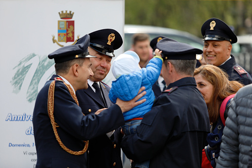 Rome, Italy - April 14, 2019: Piazza San Giovanni Bosco, uniformed police joke with a child and his mother during the event for the celebrations of the 167th anniversary of the Italian Police.