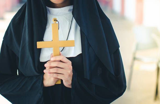 Religious nun in religion concept. Hands praying to the GOD while holding a crucifix symbol. Religious nun in religion concept. Hands praying to the GOD while holding a crucifix symbol. Nun holding a cross in his hands. Human hands holding a cross holy and prayed for blessings from God. nun praying cross human hand stock pictures, royalty-free photos & images