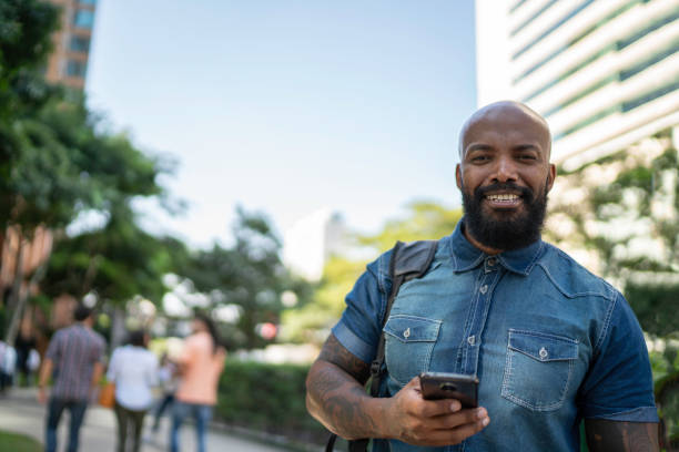 portraif do homem ao ar livre usando o telemóvel que espera alguém ou um táxi do táxi reservado com app da parte do passeio - booked - fotografias e filmes do acervo