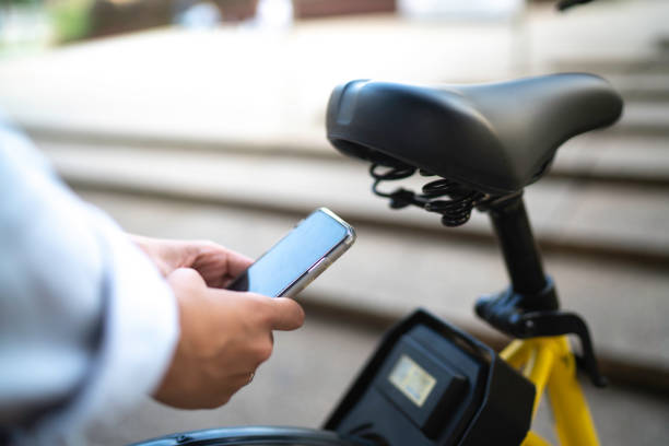 mão da mulher que usa o telemóvel para alugar uma bicicleta de uma estação da parte da bicicleta - bikeshare - fotografias e filmes do acervo