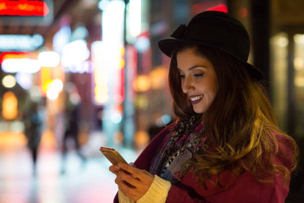 istock Young woman using phone on the street at night 1144427269
