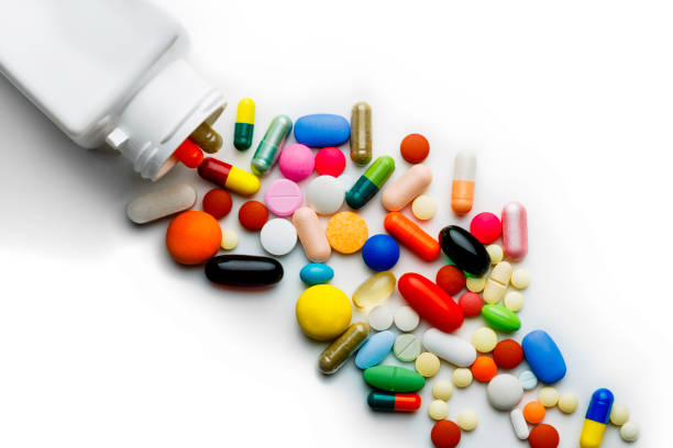 gran grupo de cápsulas variadas y pastillas que salen de la botella sobre un fondo blanco - vitamin pill vitamin c nutritional supplement bottle fotografías e imágenes de stock