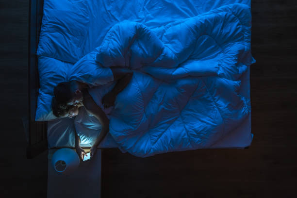 istock The couple with a phone lay on a bed. Evening night time. View from above 1144428608