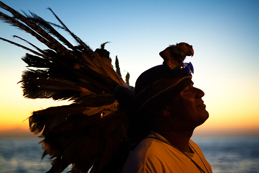 Puerto Vallarta, Mexico: A silhouette of an indigenous man in native headdress on Puerto Vallarta’s waterfront at dusk.