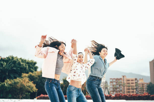 幸せなアジアの女の子が一緒に遊ぶ屋外-若い女性の友人は、大学の休憩ダンスを楽しんで、外千年世代、友情、若者のライフスタイルを祝う - 記念写真 ストックフォトと画像