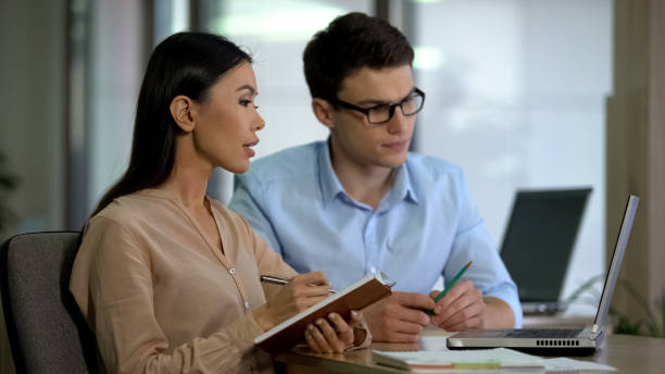 istock Young colleagues watching online training laptop making notes, planning strategy 1144431358