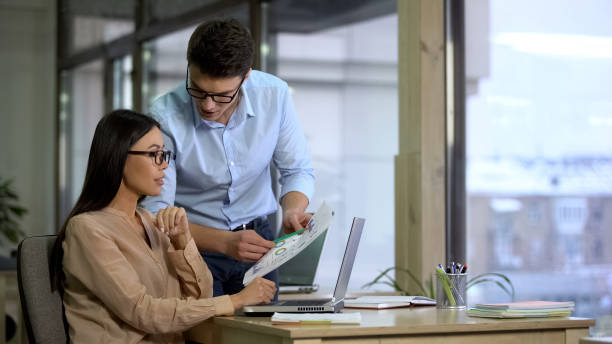 istock Financiers of large company comparing supply and demand graphs before reporting 1144431463