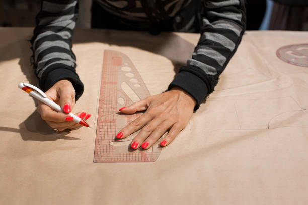 istock Female dressmaker hands tailor mark drawing on craft paper for making patterns 1144434943