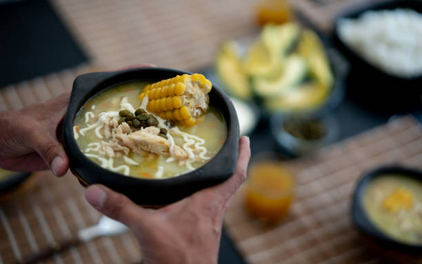 Unrecognizable person holding a delicious Ajiaco ready to serve on table