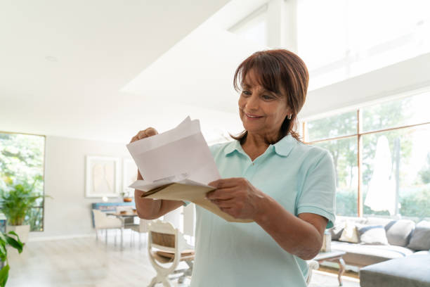 自宅で陽気な年配の女性は彼女のメールの笑顔をチェック - mail mailbox senior adult cheerful ストックフォトと画像