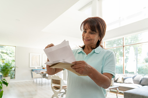 Cheerful senior woman at home checking her mail smiling