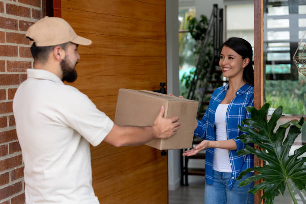 istock Friendly postal worker delivering a package to female customer at home both smiling 1144439692