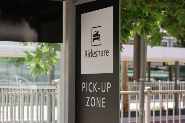 Black and white ride share pick-up zone sign Black and white rideshare pick-up zone sign. Green leaves, metal fence and sign in the background. car pooling stock pictures, royalty-free photos & images