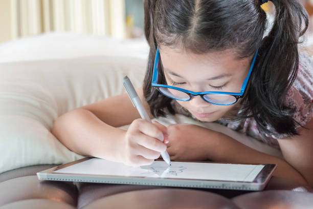 istock Asian school child girl using smart  tablet device digital technology drawing on innovative touchscreen surface 1144447504