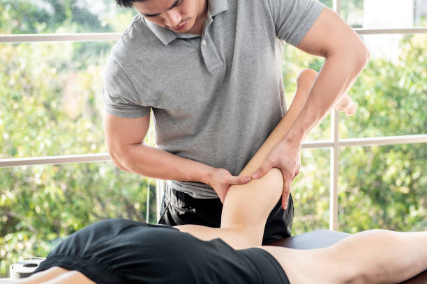 male therapist giving leg massage to athlete patient in clinic - reflexology massaging recovery sport imagens e fotografias de stock