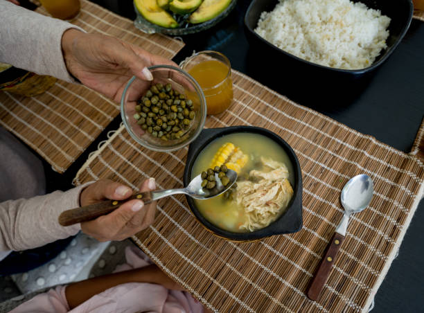 Unrecognizable person adding capers to a delicious Ajiaco