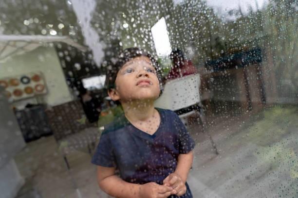 istock Cute little boy looking out the window on a rainy day 1144447605