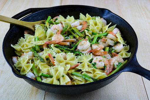 Freshly made bowtie pasta with asparagus and shrimp in a cast iron pan