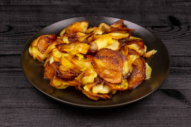 istock Fried homemade potato chips in a black plate on a wooden rustic background 1144456725