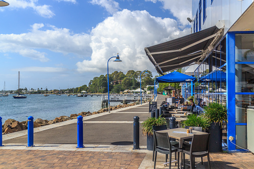 Batemans Bay, Australia - 12th February 2018: People drinking coffee in the sunshine. The promenade is a popular spot.