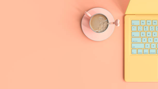 istock pastel idea concept. coffee pink cup beside laptop yellow 1144461412