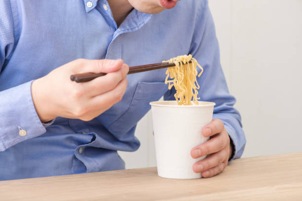istock Man eating a cup instant noodles. 1144468662