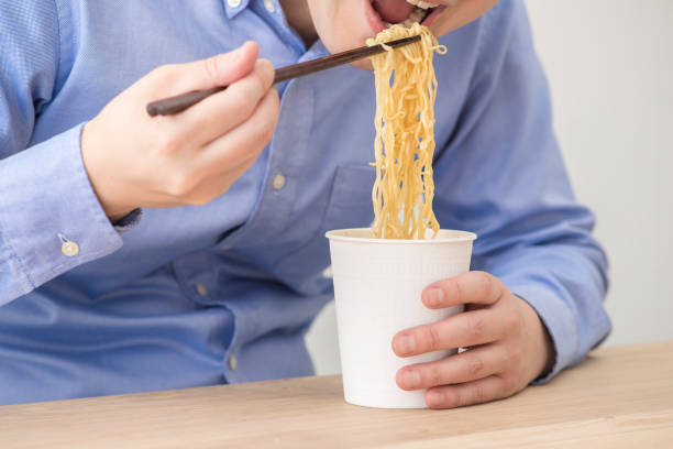 istock Man eating a cup instant noodles. 1144468778