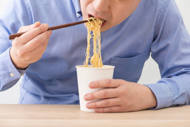 istock Man eating a cup instant noodles. 1144469392