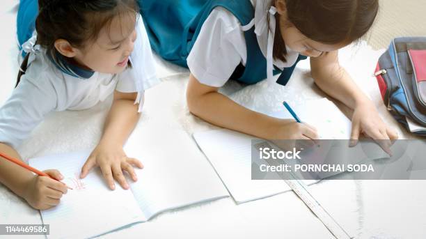Two Sister Girl Writes A Book The Decision Of Lessons Girl Lay Down Drawing The Picture Stock Photo - Download Image Now