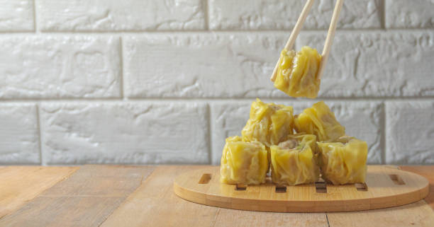 dumplings dim sum dispuestos en una bandeja de madera en la mesa de madera y fondo de ladrillo - shumai fotografías e imágenes de stock